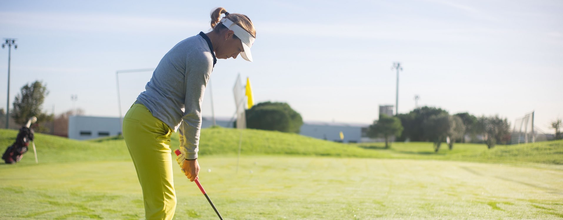 woman playing wearing a light blue sweater, white visor, yellow pants
