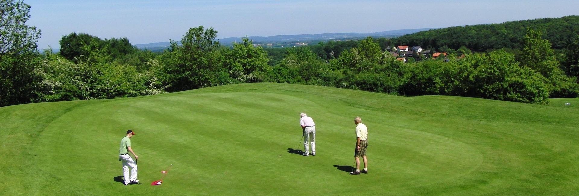 three golfers on a green putting
